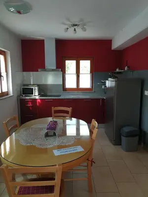 a kitchen with a wooden table and chairs and red walls at Hiša Kranjc in Kobarid