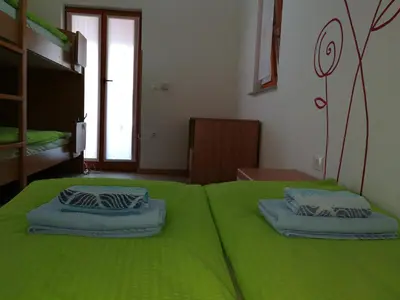 a green bed with two pillows on top of it at Hiša Kranjc in Kobarid