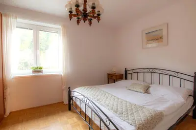 a bedroom with a bed and a window and a chandelier at Apartma Rogla Relax in Oplotnica