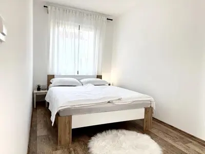 a bedroom with a bed with white sheets and a window at Spacious Cosy Apt with Pool and Parking in Pesnica pri Mariboru