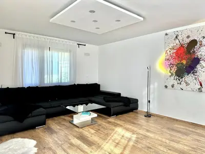 a living room with a black couch and a painting at Spacious Cosy Apt with Pool and Parking in Pesnica pri Mariboru