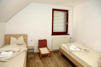 two beds in a room with a chair and a window at Weiss Sport & Relax Apartment in Rečica ob Savinji