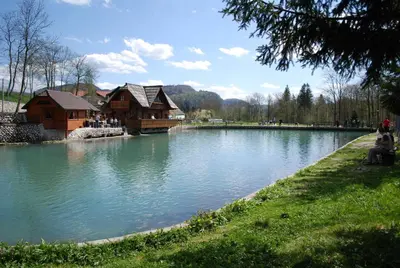 a lake with a wooden house in the middle at Apartma Mihovc in Kamnik