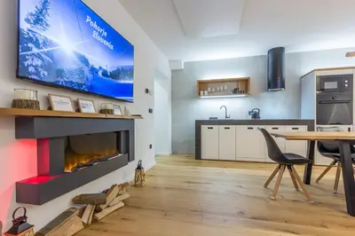 a living room with a fireplace and a tv on a wall at Charming A&S Pohorje Apartments in Pohorje