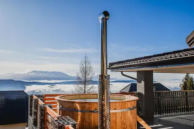 a hot tub on a deck with a view of the mountains at Holiday Home Mountainview Horizon with Private Sauna & Hot Tub in Dravograd