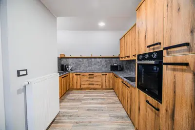 a kitchen with wooden cabinets and a black appliance at Holiday Home Mountainview Horizon with Private Sauna & Hot Tub in Dravograd