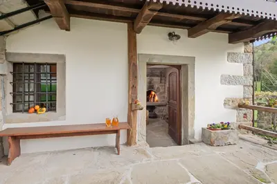 a porch of a house with a bench and a fireplace at Hiška Kovačija in Vremski Britof