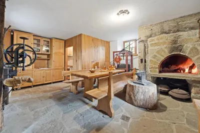 a living room with a stone fireplace and a wooden table at Hiška Kovačija in Vremski Britof