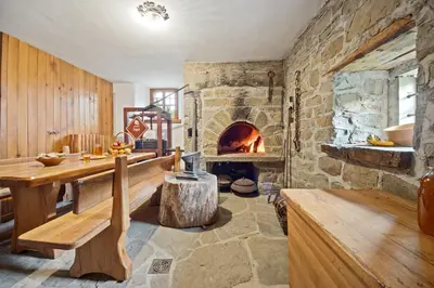 a living room with a stone fireplace and a wooden table at Hiška Kovačija in Vremski Britof