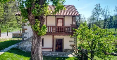 a small house with a balcony and a tree at Hiška Kovačija in Vremski Britof