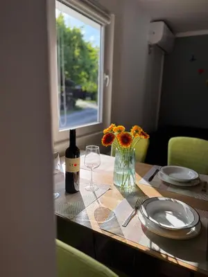 a table with a bottle of wine and a vase of flowers at House of Eden- Private Family Holiday Home in Terme Catez with FREE Pool Tickets in Čatež ob Savi