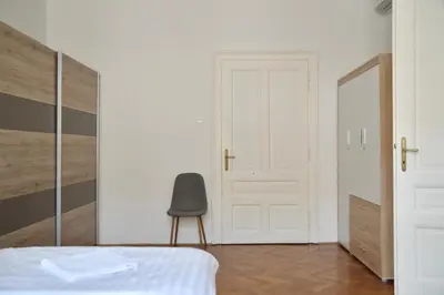 a bedroom with a white bed and a chair at Apartment Trdinova in Ljubljana