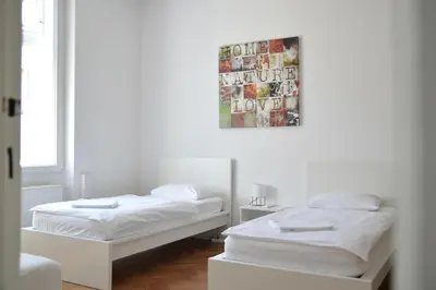 two beds in a white room with a picture on the wall at Apartment Trdinova in Ljubljana