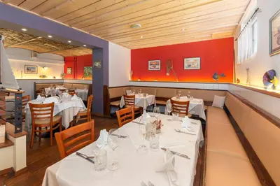 a restaurant with white tables and chairs and red walls at Apartments Tabor in Naklo