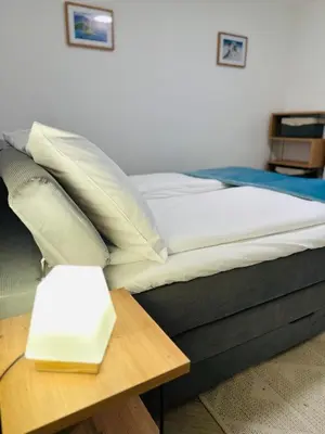 a bed with white pillows and a wooden table at Montis Bled in Bled