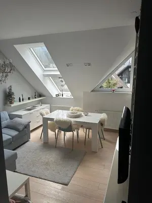 a white living room with a table and some windows at Kranjska Gora Urban Apartment in Kranjska Gora