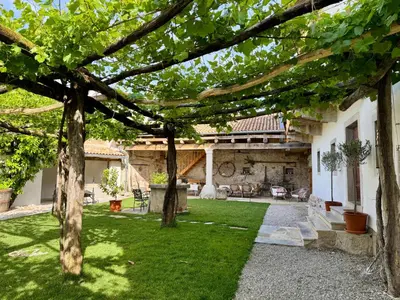 a yard with trees and a building with a patio at Vila Kobdilj 1835 Historic Homestead with Shared Courtyard in Štanjel
