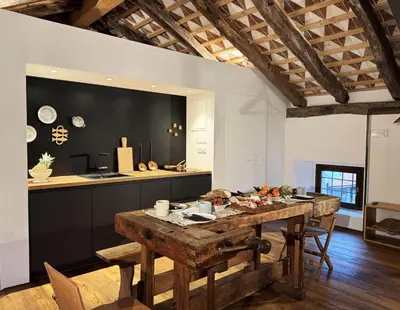 a kitchen and dining room with a wooden table at Vila Kobdilj 1835 Historic Homestead with Shared Courtyard in Štanjel