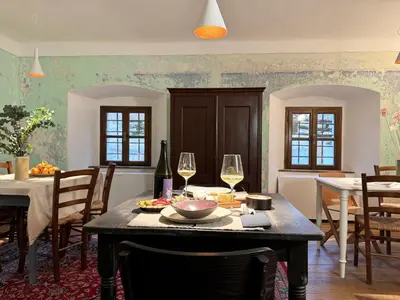 a dining room with a table with glasses of wine at Vila Kobdilj 1835 Historic Homestead with Shared Courtyard in Štanjel