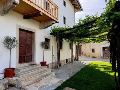 a house with a wooden door and a yard at Vila Kobdilj 1835 Historic Homestead with Shared Courtyard in Štanjel