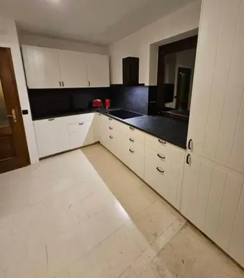 a kitchen with white cabinets and black counter tops at Orchard Villa in Bled