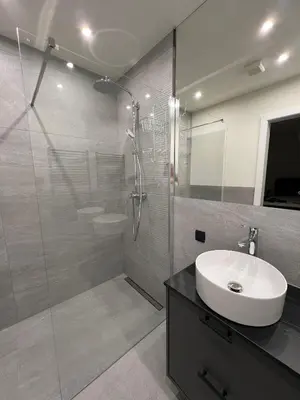 a bathroom with a glass shower and a sink at Orchard Villa in Bled