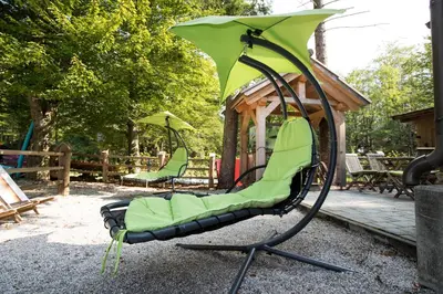 a green swing chair in front of a gazebo at Hiša Erlah in Bohinj