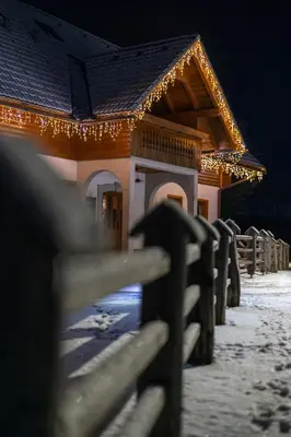 a fence in front of a house with christmas lights at Hiša Erlah in Bohinj