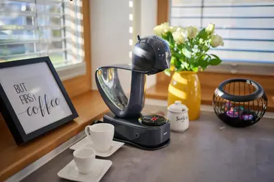 a coffee maker on a table with cups and flowers at Chili apartment in Žabnica