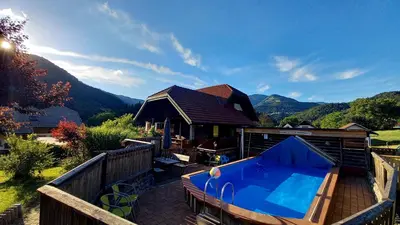a house with a swimming pool on a deck at Apartments Pri Boštjanovcu in Gorenja Vas