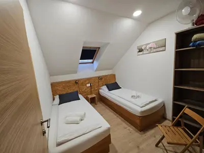 a small room with two beds and a shelf at Apartments Pri Boštjanovcu in Gorenja Vas