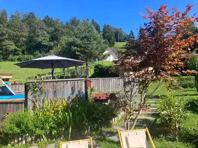 a garden with a fence and an umbrella at Apartments Pri Boštjanovcu in Gorenja Vas