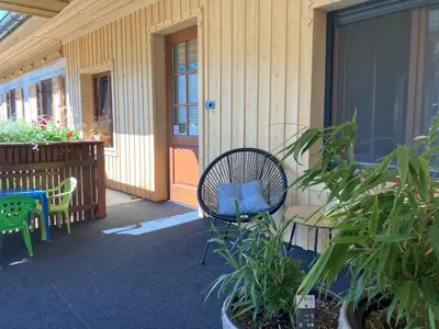 a patio with a chair and some plants and a building at Apartments Pri Boštjanovcu in Gorenja Vas