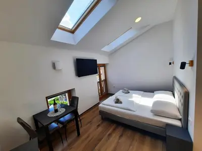 a bedroom with a bed and a table and a skylight at Apartments Hlapi with SPA in Kobarid