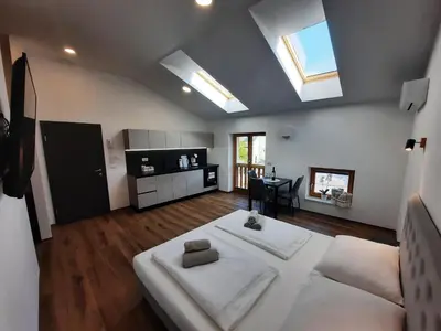 a living room with a large white bed and a kitchen at Apartments Hlapi with SPA in Kobarid