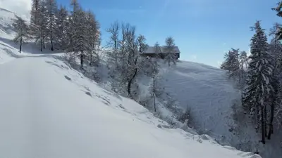 a snow covered hill with a house on top of it at Glamping apartma Oaza miru in Preddvor