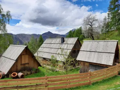 three barns in a field with a fence at Glamping apartma Oaza miru in Preddvor
