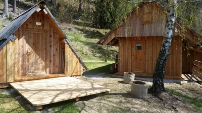 a wooden cabin with a wooden floor and a tree at Glamping apartma Oaza miru in Preddvor