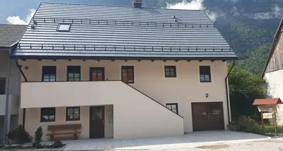 a white house with a black roof at APARTMAJI VITEZ Apartma 4 in Bovec