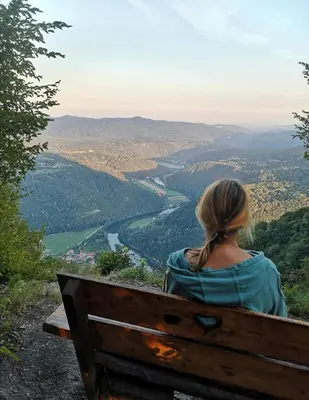 a woman sitting on a bench overlooking a valley at Art & Sun in Kočevje