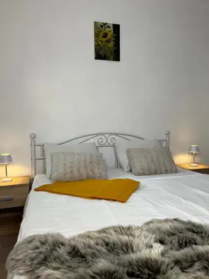 a large white bed with a yellow blanket on it at Apartments Linden Tree in Kamnik