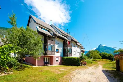 a building with a mountain in the background at Apartma BAZA in Bovec