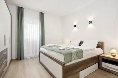 a white bedroom with a bed and a window at Kristal Lux Aparments with a balcony in Rogaška Slatina