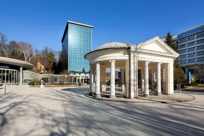 a white building with pillars in the middle of a street at Kristal Lux Aparments with a balcony in Rogaška Slatina