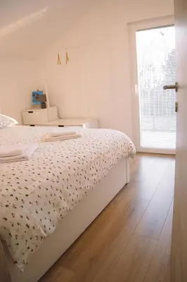 a white bedroom with a bed and a window at Zelena harmonija in Moravske Toplice