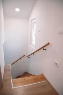 a staircase with a wooden rail and a window at Zelena harmonija in Moravske Toplice