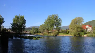 a river with a bridge and trees and houses at Apartmaji in sobe RaMar in Straža