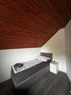 a bed in a room with a wooden ceiling at Larisa apartma in Domžale