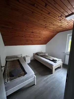 two beds in a room with a wooden ceiling at Larisa apartma in Domžale
