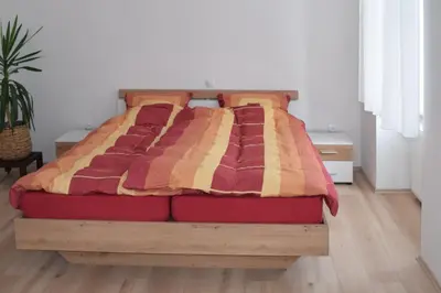 a bed with a wooden frame with a blanket on it at Apartma Majerhold in Mozirje